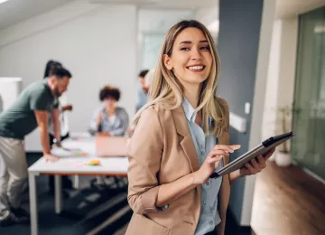 Mujer sonriendo con ipad a la derecha de la foto